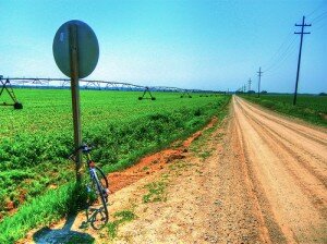 road sign on a dirt road next to a farm 